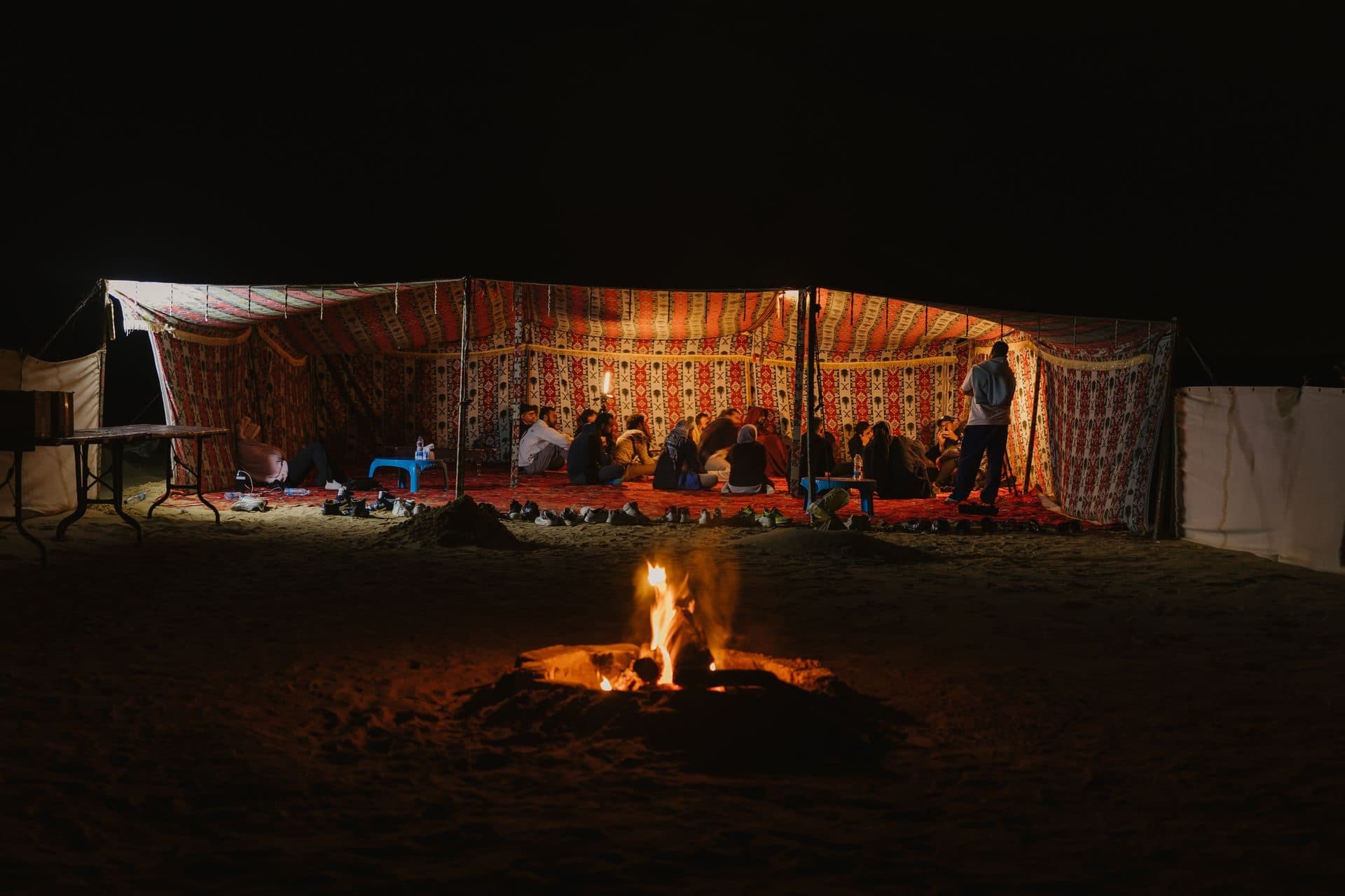 Travellers gathered around the fire at a desert camp
