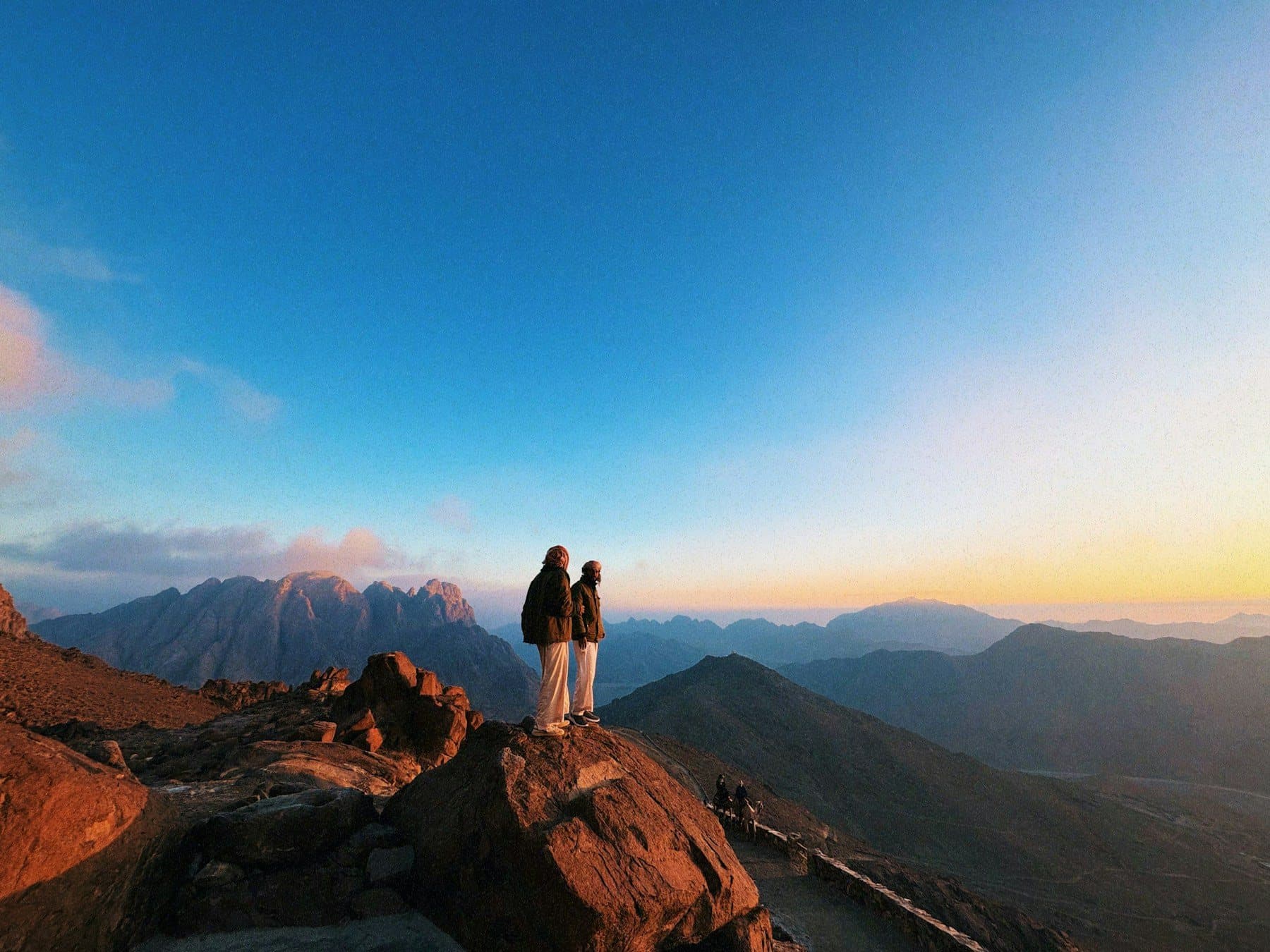 Two travellers watching the sunrise from the summit of Mount Sinai