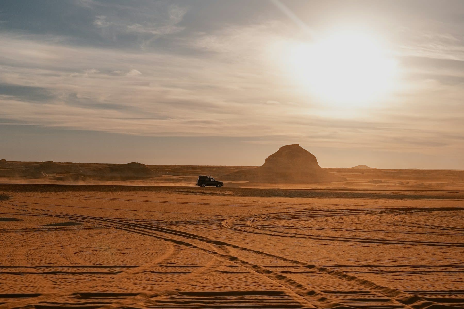 A 4x4 crossing the desert at sunset